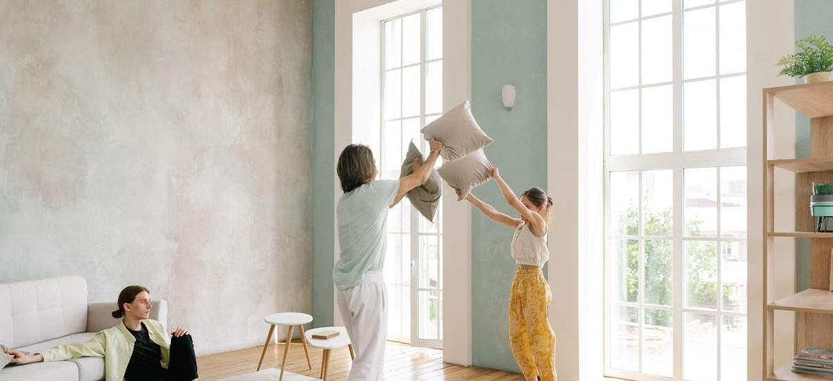Family enjoying a playful pillow fight in a spacious modern living room.