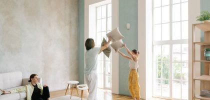 Family enjoying a playful pillow fight in a spacious modern living room.