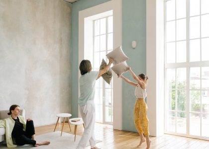 Family enjoying a playful pillow fight in a spacious modern living room.